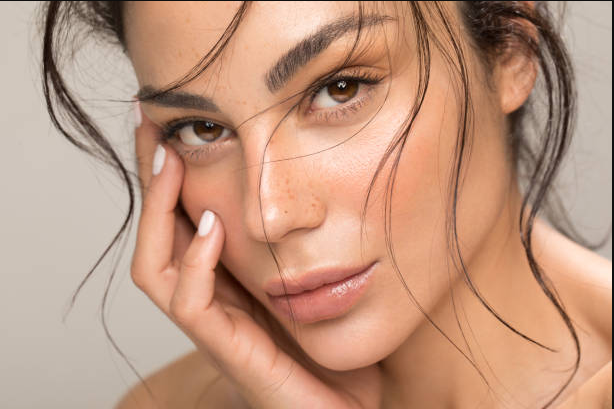 Sinnliche Nahaufnahme einer jungen Frau mit makelloser Haut, vollen Lippen und natürlichen Sommersprossen