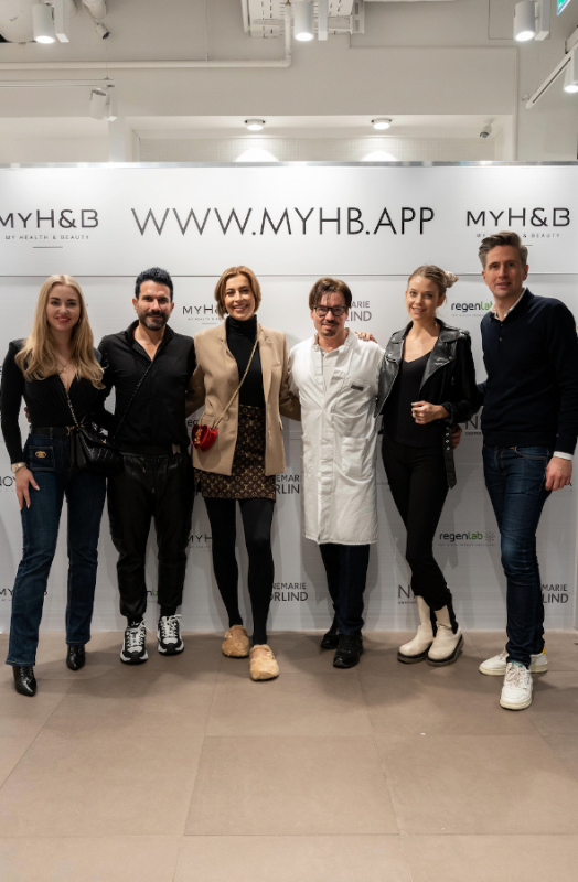 Gruppenbild mit MYH&B Team und prominenten Gästen bei Event mit gebrandetem Hintergrund und guter Stimmung