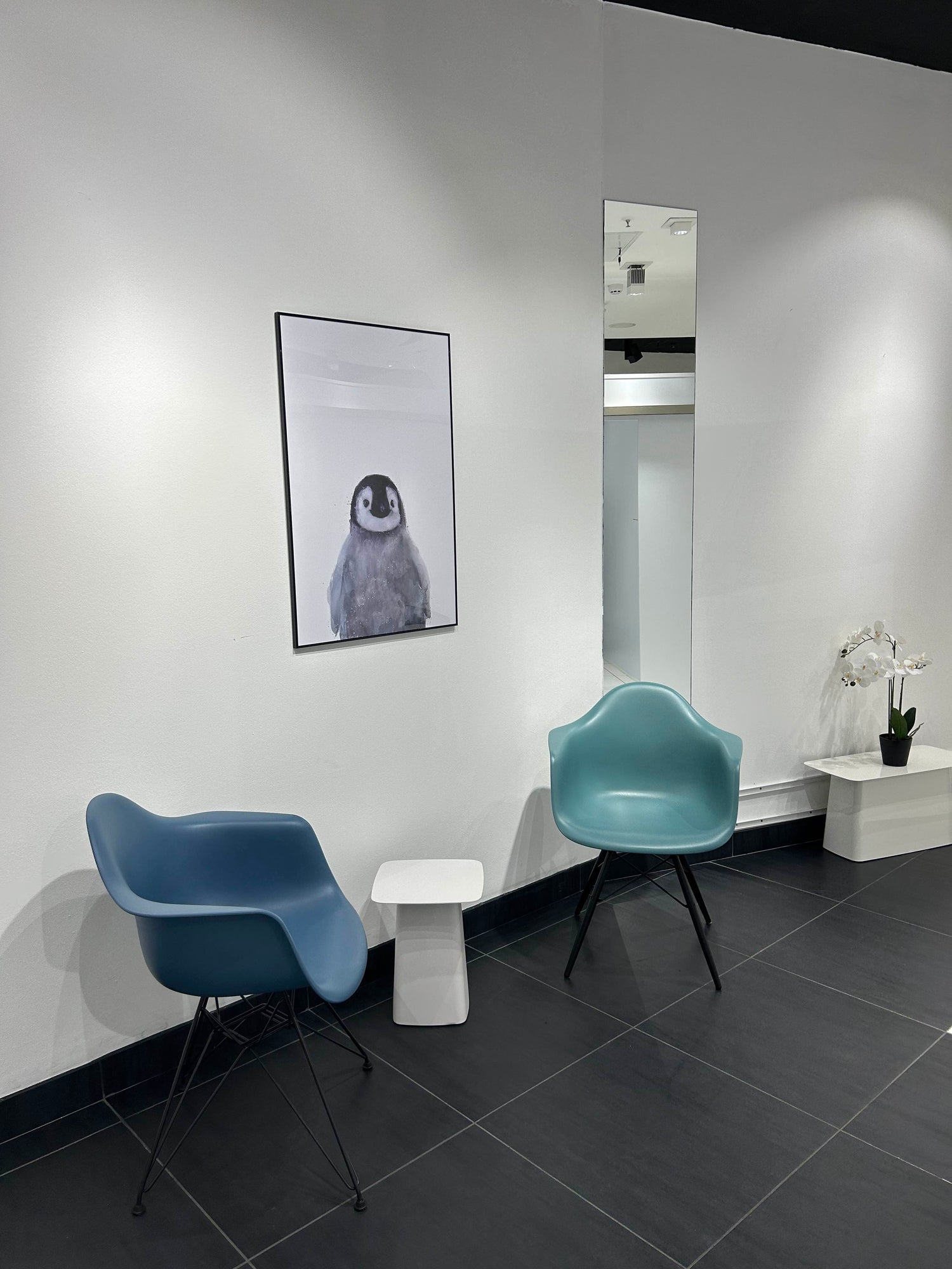 Wartebereich bei MYH&B mit zwei modernen Sesseln, Beistelltisch und Pinguinbild