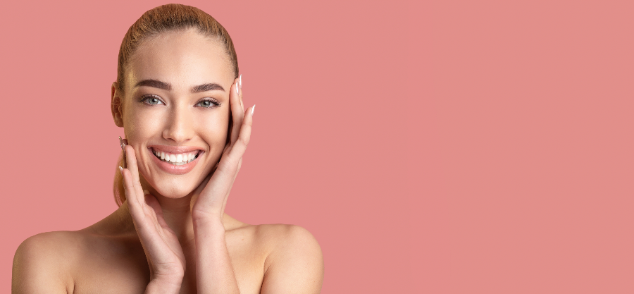 Lächelnde Frau mit strahlender Haut vor rosa Hintergrund – Sinnbild für Zufriedenheit nach Beauty-Behandlung.