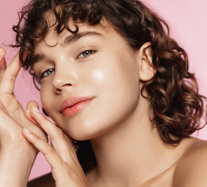 Junge Frau mit makellosem Gesicht lächelt leicht